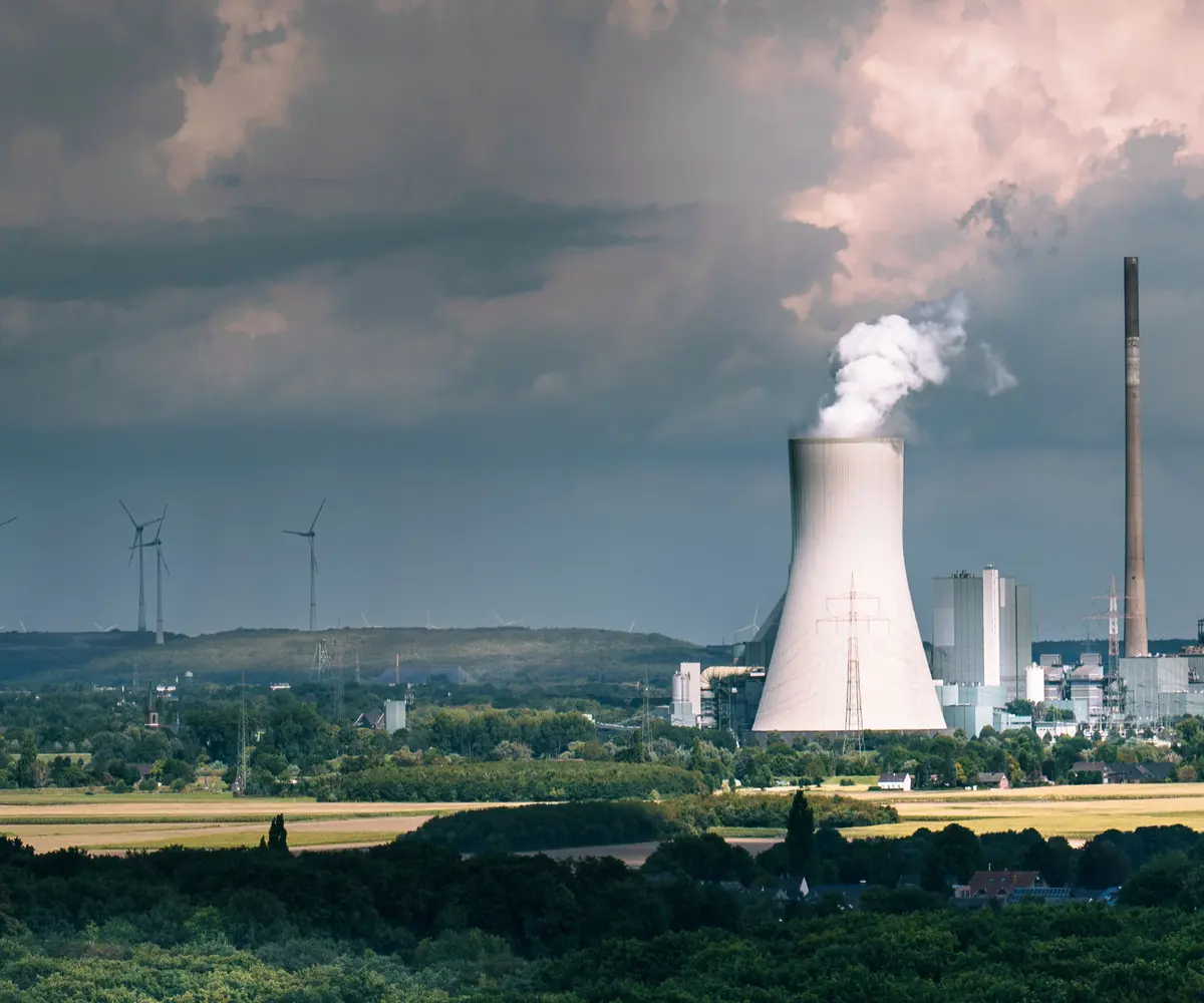 Instalacja przemysłowa na tle krajobrazu i turbin wiatrowych